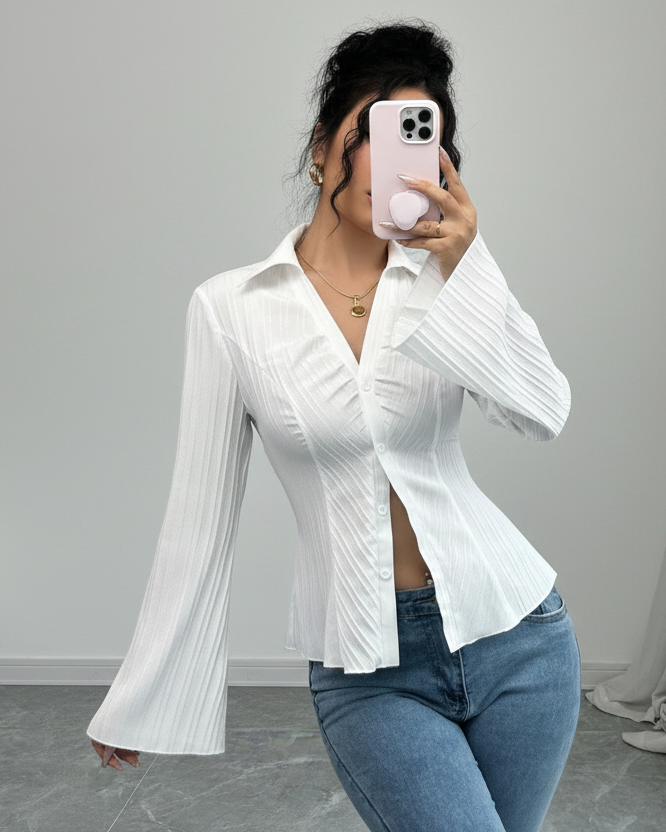 Person wearing a white blouse with bell sleeves and blue jeans, taking a mirror selfie.